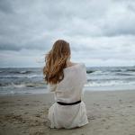 photo of young lonely depressed woman on cold windy beach