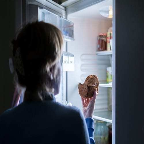 woman opening refrigerator to eat