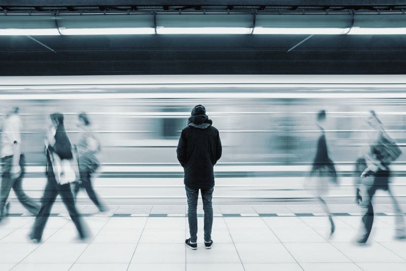 Loneliness in our world, man standing alone with the world passing him by