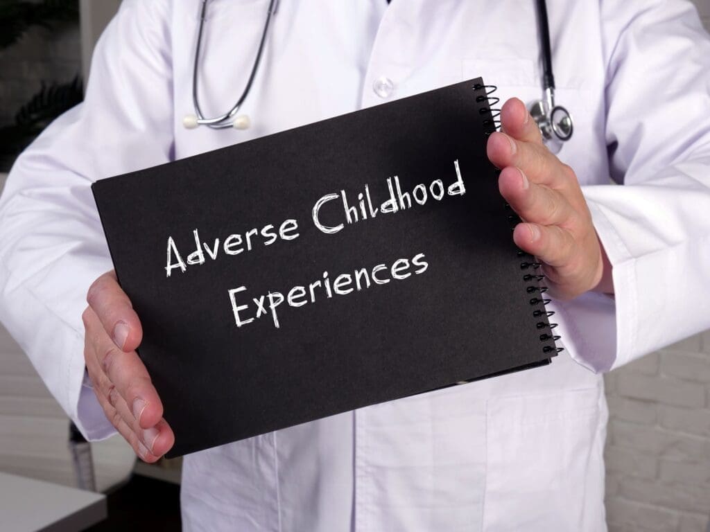A physician holding an adverse childhood experiences sign. The office of Ginny Estupinian treats adverse childhood trauma