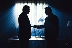 photo of two businessmen doing a deal in the dark to depict business betrayal 