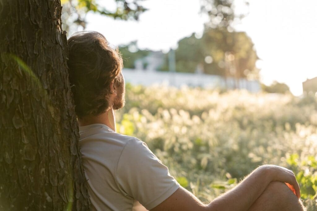 Photo of a man relaxing against a tree allowing his mind to get quite