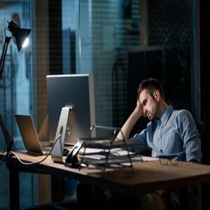Photo of a man sitting slouched with an exhausted expression, resting his head in his hands, visually portraying fatigue as a symptom of anxiety