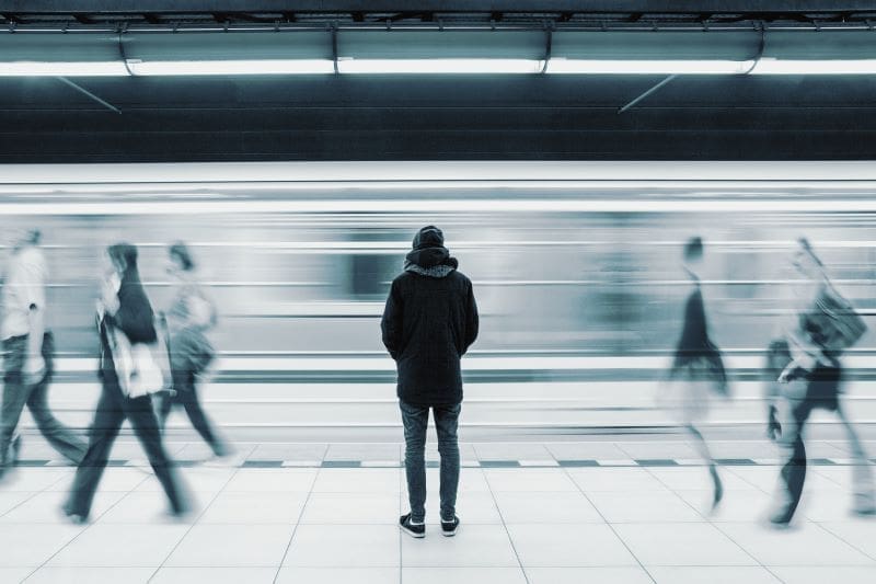Image of a man standing alone, symbolizing loneliness as the world moves past him, highlighting feelings of isolation