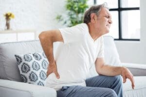 Photo of an older man experiencing back pain, potentially linked to depression, highlighting the connection between physical and mental health
