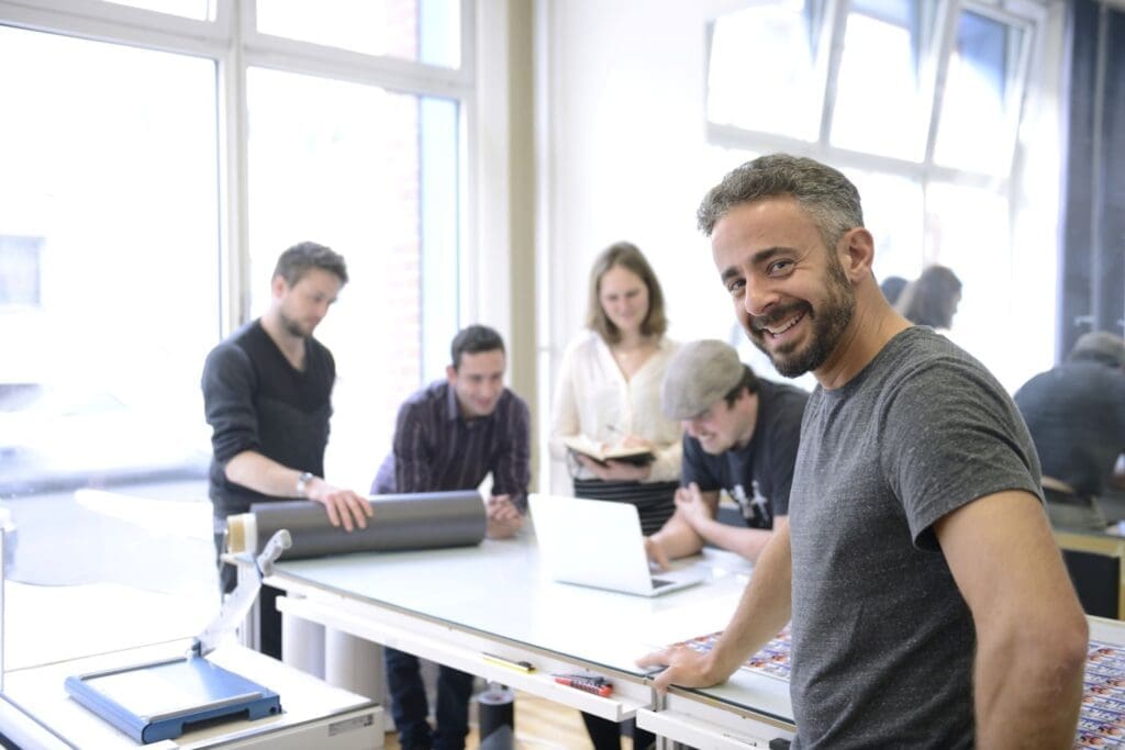 Business owner with smiling team—Ginny Estupinian PhD boosts workplace performance