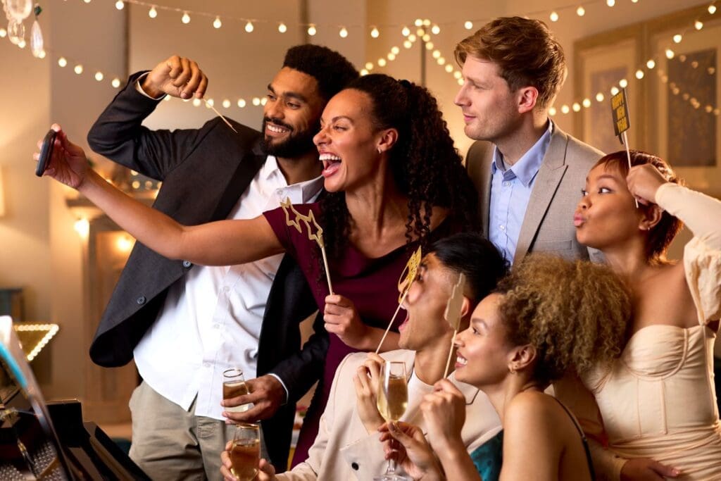 A photo of young adults taking a group selfie for social media, illustrating Dr. Ginny Estupinian, PhD’s insights on how social media comparison contributes to stress and anxiety.