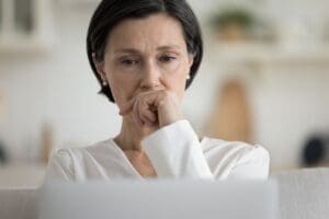 Photo of a businesswoman contemplating the demands on her time from professional, to mother, to caregiver of older adult.